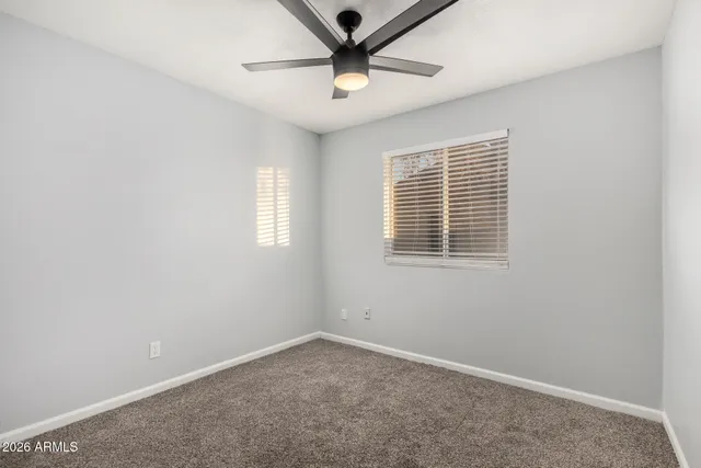 an empty room with a window and a ceiling fan