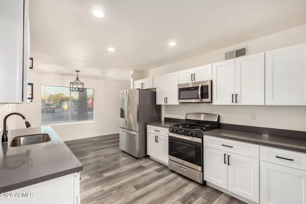 a kitchen with granite countertop a sink stainless steel appliances and white cabinets