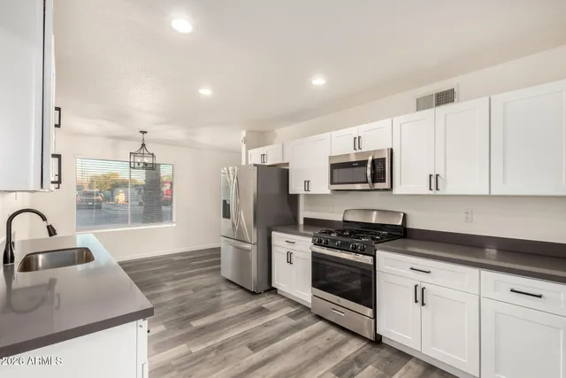 a kitchen with granite countertop a sink stainless steel appliances and white cabinets