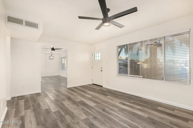 a view of empty room with wooden floor and fan