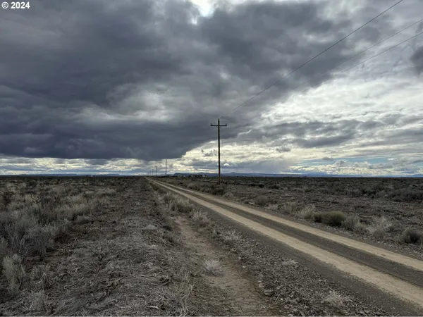 a view of a dry yard with wooden fence