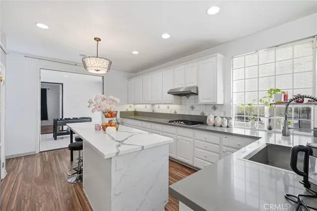 a kitchen with kitchen island granite countertop a sink cabinets and wooden floor