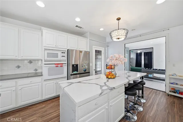 a very nice looking open kitchen with stainless steel appliances granite countertop a stove and white cabinets