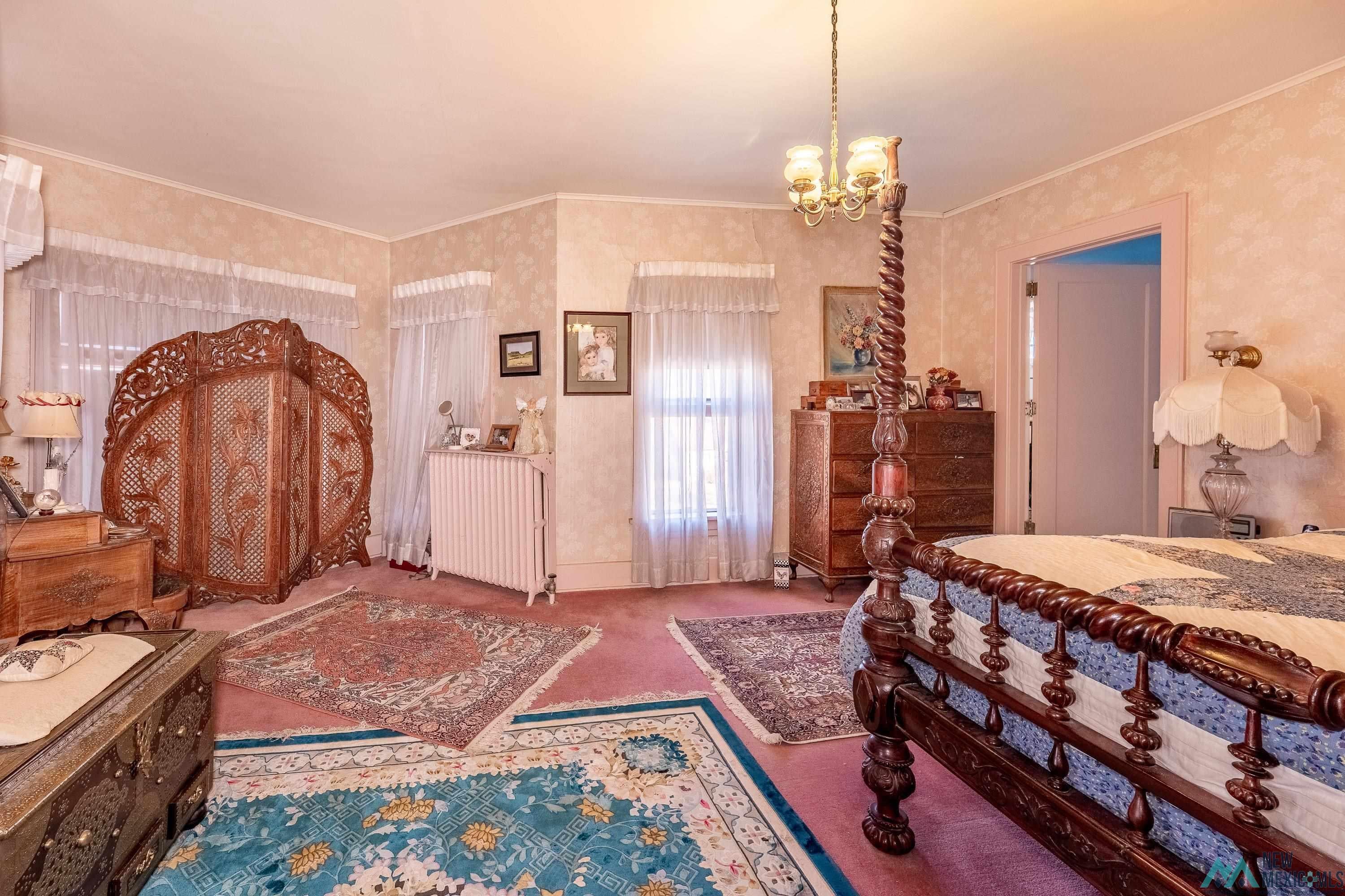 301 South 4th Street Raton, NM 87740 - Photo 18 of 78 Bedroom featuring radiator heating unit, ornamental molding, a chandelier, and carpet