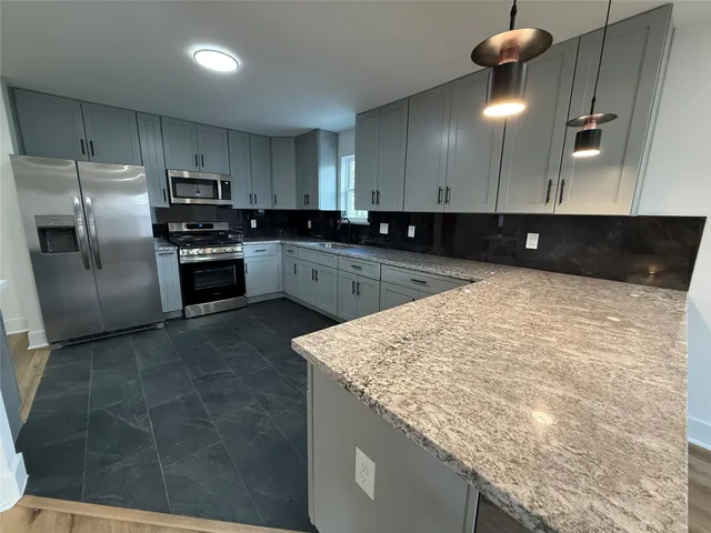 a kitchen with stainless steel appliances granite countertop a sink a stove and a refrigerator