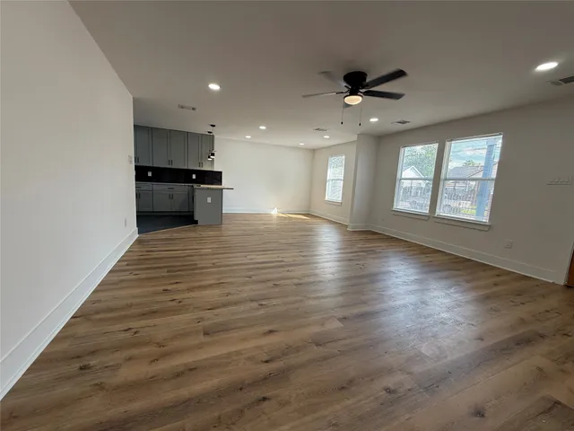 an empty room with wooden floor cabinet and windows