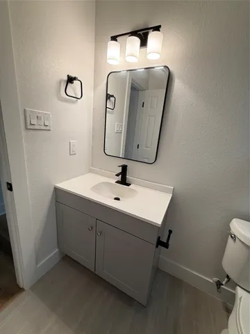 a bathroom with a sink and mirror with toilet