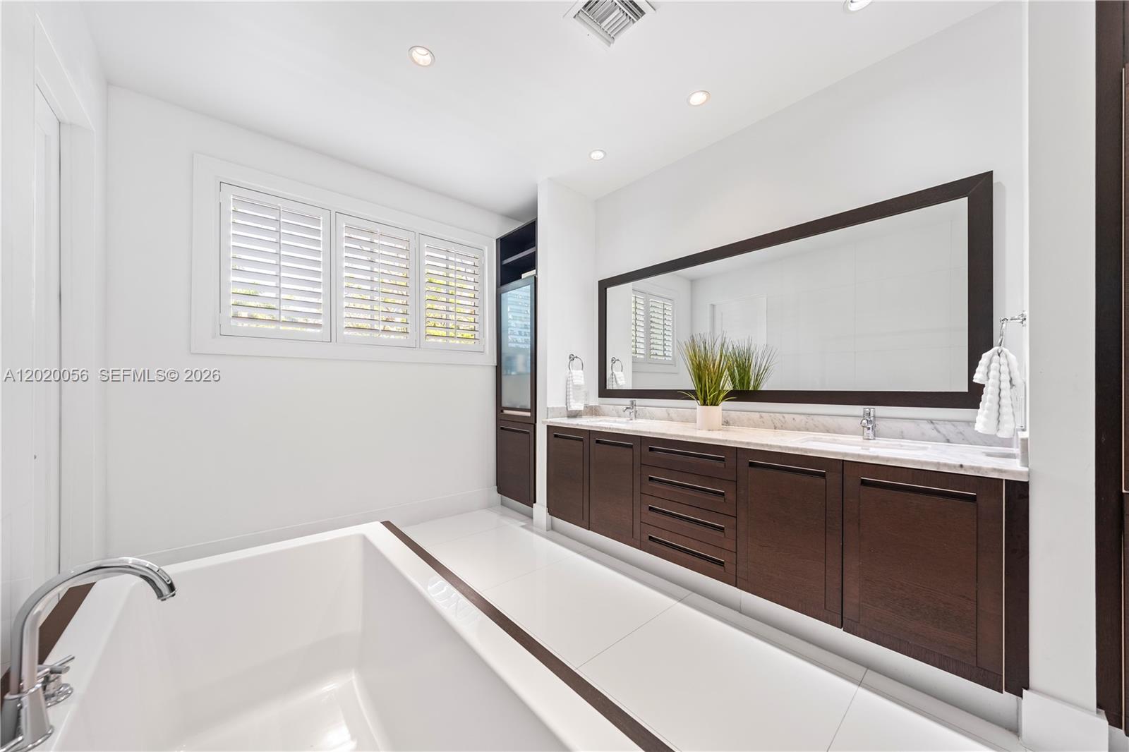 4196 Douglas Road Miami, FL 33133 - Photo 55 of 96 a bathroom with a double vanity sink and mirror