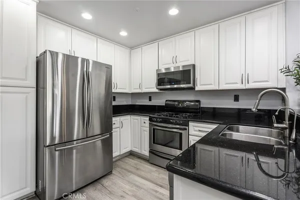 a kitchen with granite countertop a sink stainless steel appliances and white cabinets