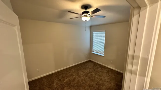 an empty room with a window and a ceiling fan