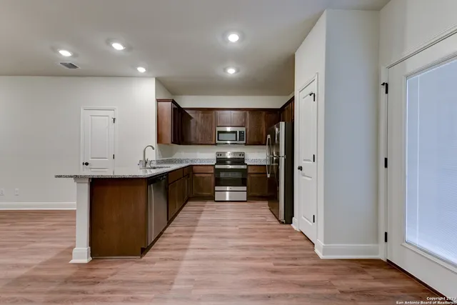 a large kitchen with stainless steel appliances kitchen island granite countertop a large counter top and a stove top oven