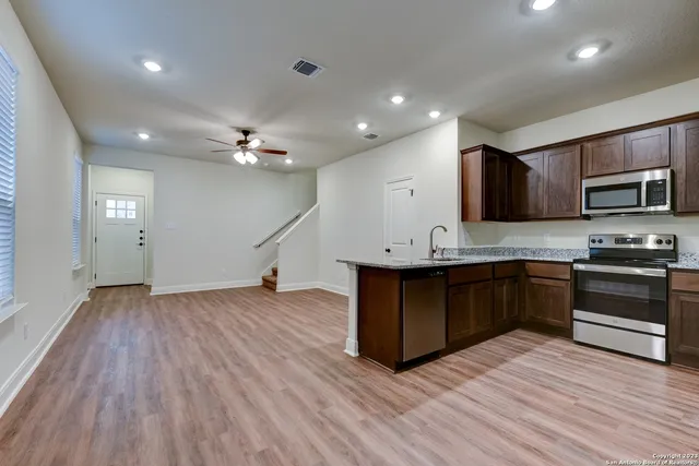 a kitchen with stainless steel appliances granite countertop a sink dishwasher a stove and a microwave oven with cabinets