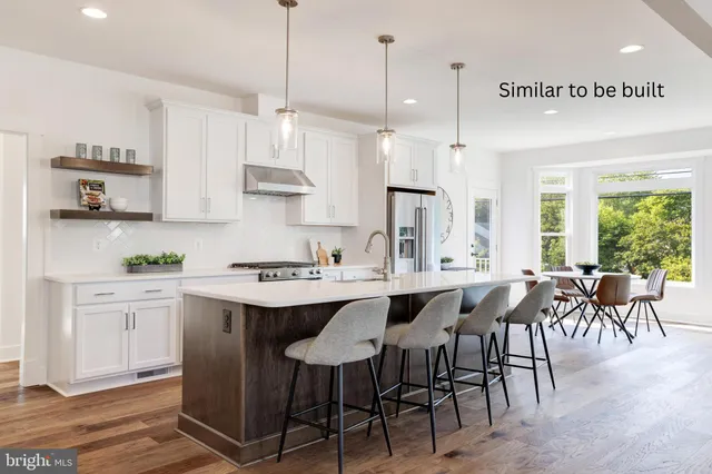 a kitchen with stainless steel appliances granite countertop a sink a stove a refrigerator and island with wooden floor