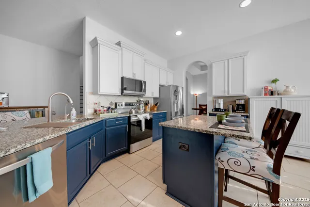a kitchen with kitchen island granite countertop a sink counter top space appliances and cabinets