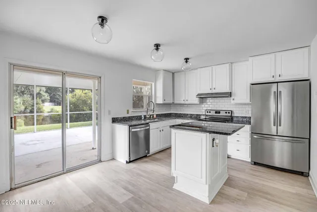 a kitchen with granite countertop a refrigerator stove top oven and sink