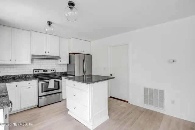 a kitchen with granite countertop a sink cabinets and stainless steel appliances