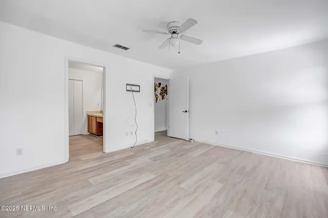 an empty room with wooden floor and ceiling fan