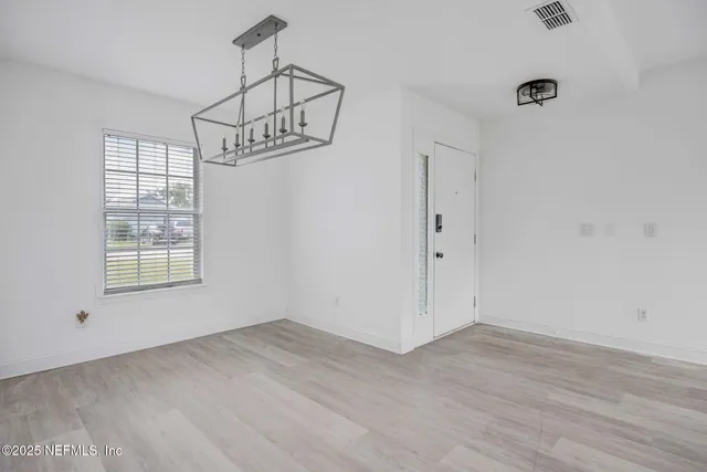 a view of an empty room with wooden floor and windows
