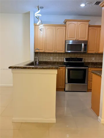 a kitchen with granite countertop a sink cabinets and stainless steel appliances