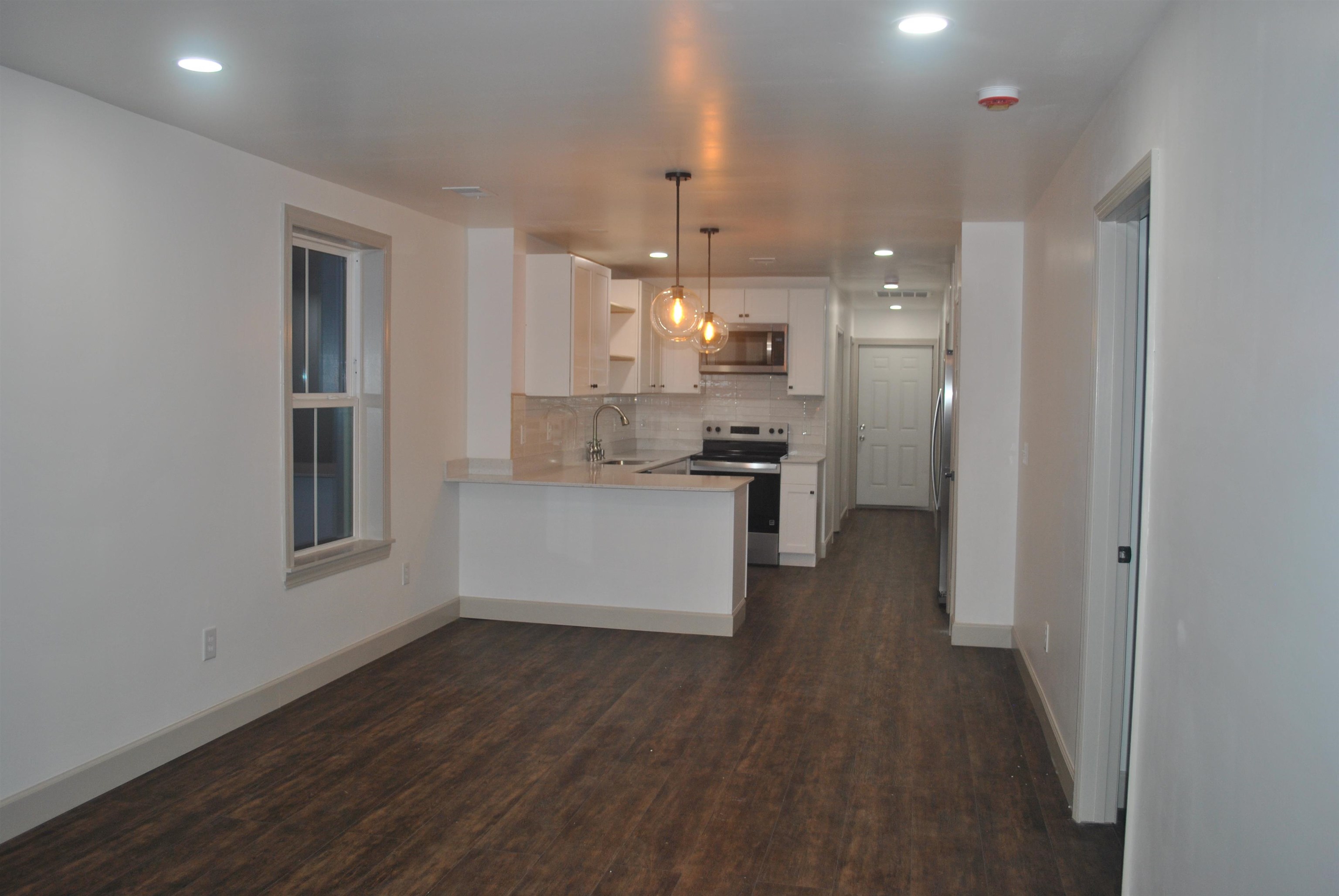 815 North Congdon Street Georgetown, SC 29440 - Photo 7 of 28 Kitchen with white cabinetry, a peninsula, stainless steel appliances, dark wood finished floors, and decorative light fixtures