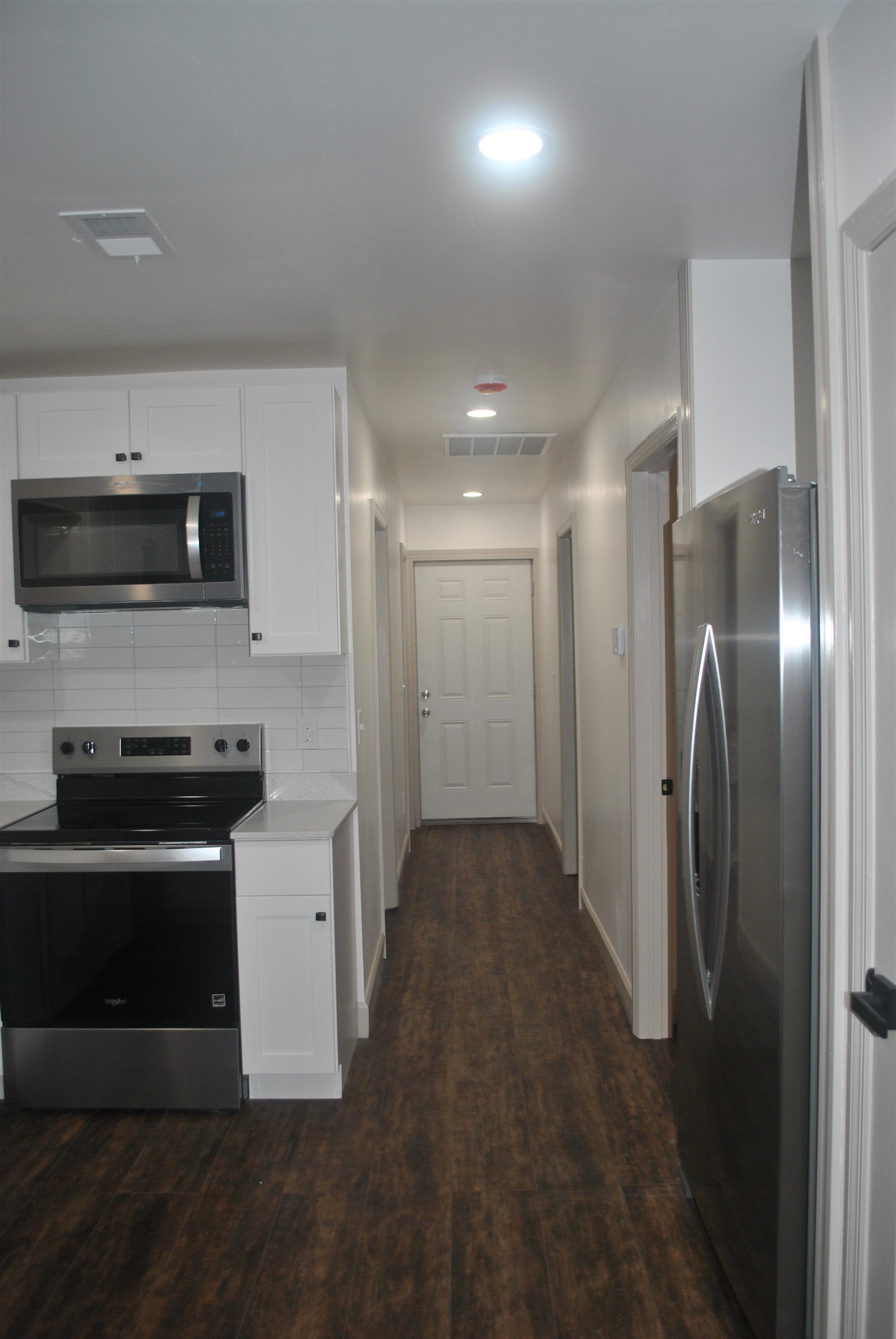 815 North Congdon Street Georgetown, SC 29440 - Photo 9 of 28 Kitchen featuring stainless steel appliances, white cabinetry, dark wood-style floors, backsplash, and light stone countertops