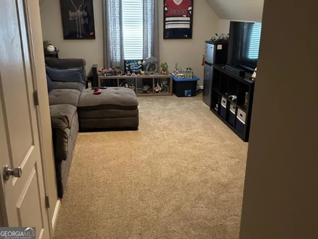 a living room with furniture a flat screen tv and a refrigerator