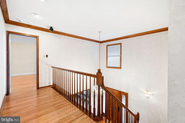 a view of a hallway with wooden floor and a bathroom