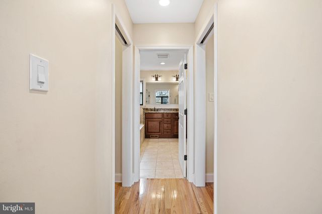 a view of a hallway with wooden floor and a bathroom