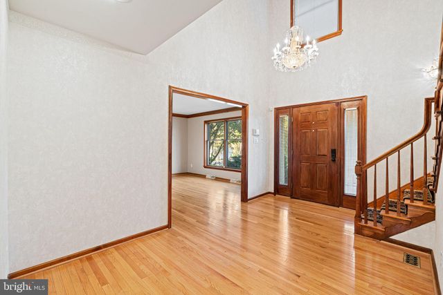 an empty room with wooden floor chandelier and windows