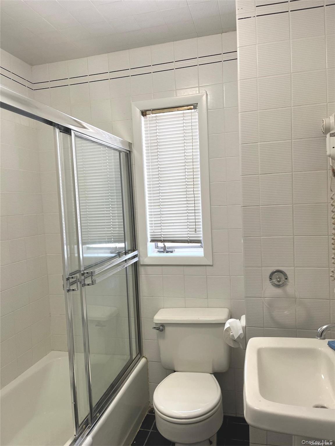 307 Magnolia Boulevard, Unit UPPR Long Beach, NY 11561 - Photo 14 of 17 a white toilet sitting next to a bath tub
