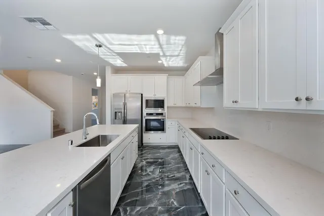 a large white kitchen with a large counter top appliances and cabinets