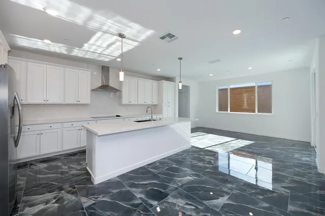 a large white kitchen with kitchen island a sink stainless steel appliances and cabinets