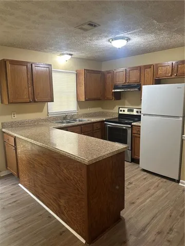 a kitchen with stainless steel appliances granite countertop a stove a refrigerator a sink a microwave and wooden cabinets