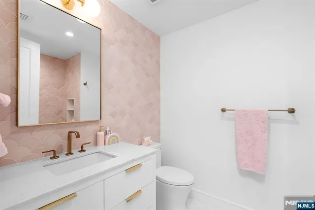 a bathroom with a granite countertop sink mirror vanity and toilet