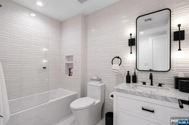 a bathroom with a granite countertop sink a toilet and bathtub
