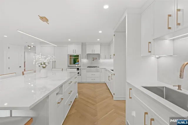 a large kitchen with stainless steel appliances kitchen island granite countertop a sink a stove and cabinets