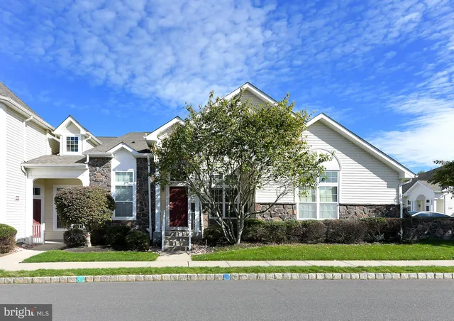 a view of a white house next to a yard with big trees