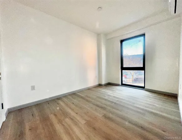 a view of an empty room with wooden floor and windows