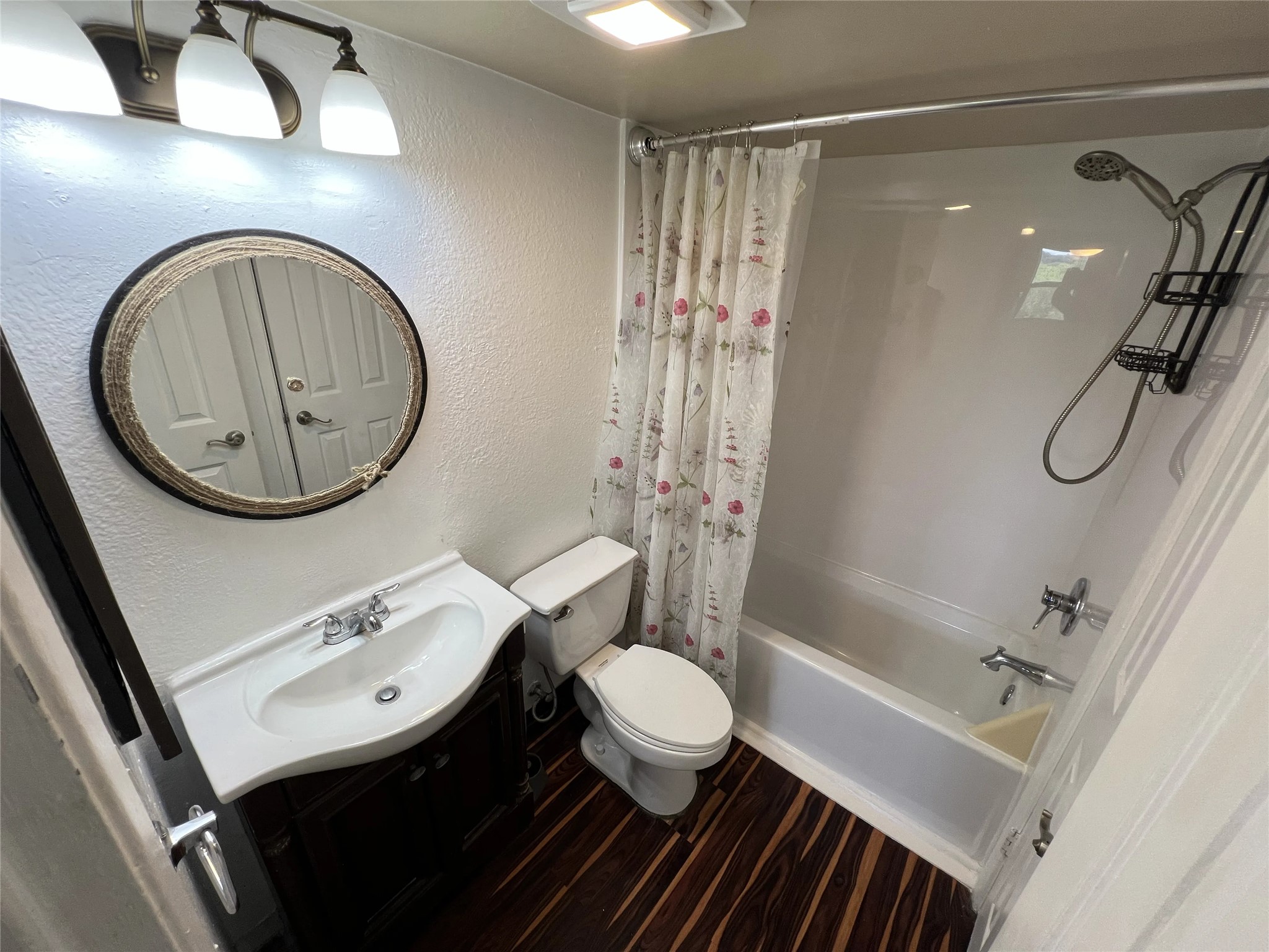2500 Burleson Road, Unit 622 Austin, TX 78741 - Photo 5 of 17 A compact bath features a crisp white vanity, essential toilet, and full bath with a floral shower curtain.