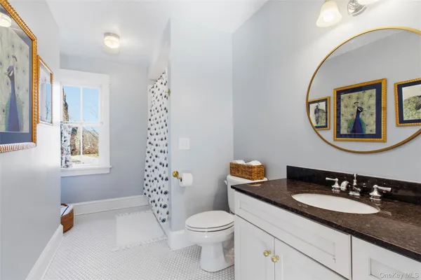 a bathroom with a granite countertop toilet a sink and a mirror