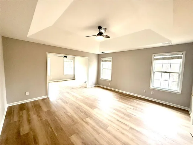 a view of empty room with wooden floor and fan