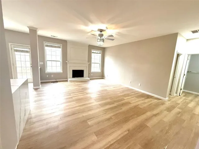 a view of a livingroom with a fireplace a ceiling fan and wooden floor