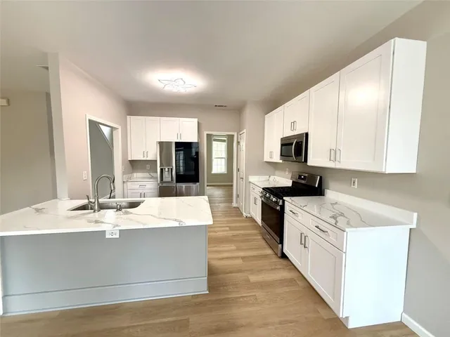 a kitchen with stainless steel appliances white cabinets white and wooden floors