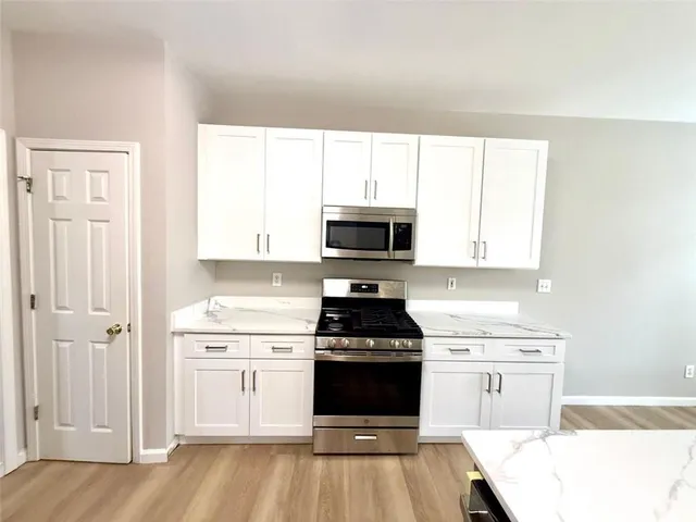 a view of a kitchen with kitchen island a sink wooden floor and stainless steel appliances