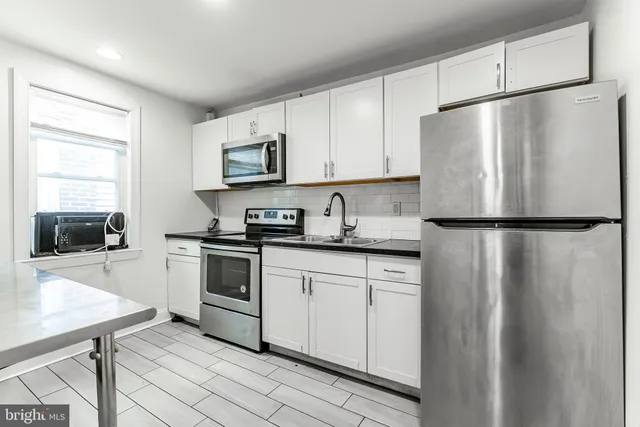 a kitchen with stainless steel appliances granite countertop a refrigerator a stove a sink and white cabinets