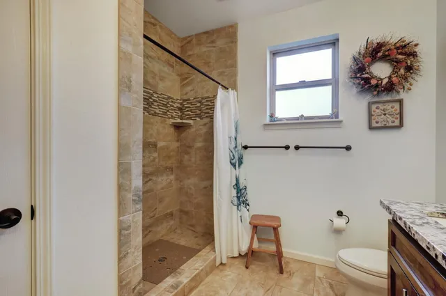a bathroom with a granite countertop sink a toilet and mirror