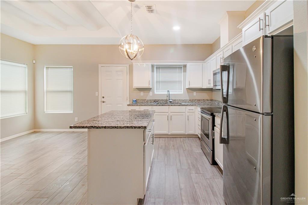 1817 Stauffer Street, Unit 2 Weslaco, TX 78596 - Photo 4 of 12 Kitchen with stainless steel appliances, light stone countertops, a center island, and white cabinetry