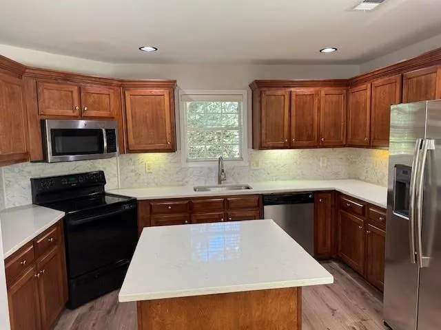 a kitchen with a refrigerator a sink a stove a microwave and wooden cabinets