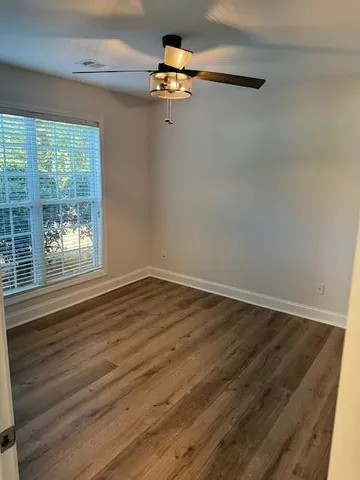 a view of empty room with wooden floor and fan