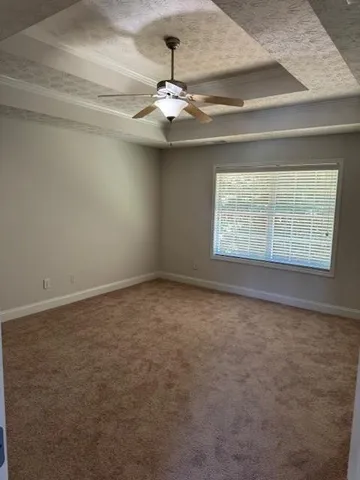 an empty room with a chandelier fan and windows